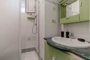 Ein Badezimmer mit Dusche, Waschbecken und Spiegel.