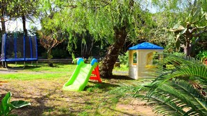 Une aire de jeux avec un toboggan, une structure d’escalade et une petite maison de jeu.