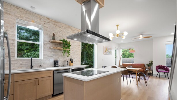 A modern kitchen with a central island, built-in appliances, and a dining area with a wooden table and chairs. - Luxury modern 3bd/3ba, sauna, EV charger, 15mi BNA 7mi Broadway 6mi Vandy (Nashville)