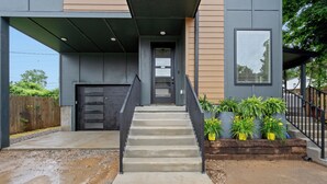 A modern house with a concrete staircase leading to a dark door, surrounded by a gravel driveway and potted plants. - Luxury modern 3bd/3ba, sauna, EV charger, 15mi BNA 7mi Broadway 6mi Vandy (Nashville)