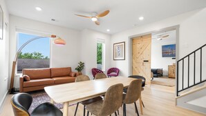 A modern living room with a wooden dining table, leather sofa, and a ceiling fan. - Luxury modern 3bd/3ba, sauna, EV charger, 15mi BNA 7mi Broadway 6mi Vandy (Nashville)