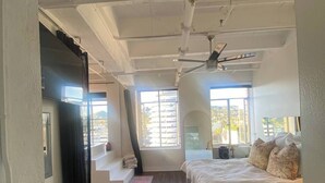 Een slaapkamer met een bed, een plafondventilator en een raam.