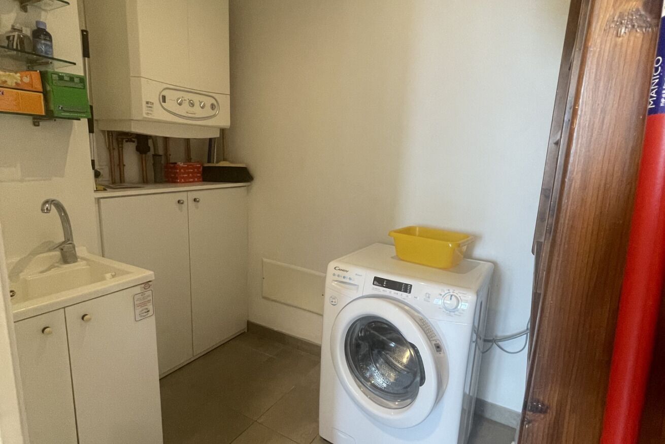 A compact laundry room with a washing machine, a sink, and cabinets.