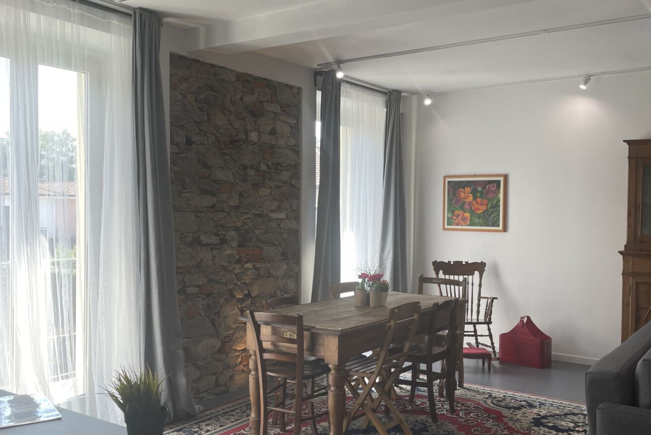A dining area with a wooden table and chairs, a stone wall, and a painting on the wall.
