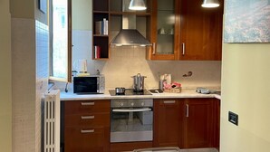 Une cuisine dotée de meubles en bois, d’un four encastré, d’un four à micro-ondes et de luminaires suspendus.