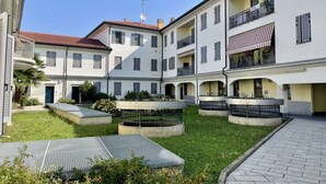 Une cour intérieure avec une fontaine centrale, entourée d’immeubles à plusieurs étages dotés de balcons et d’auvents.