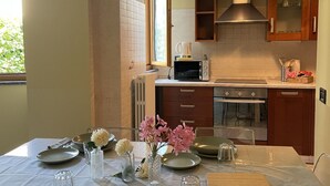 Une cuisine équipée d’une table à manger pour deux personnes, d’un four à micro-ondes, d’un four traditionnel et de placards en bois.
