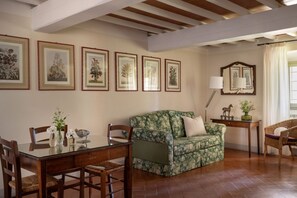Una sala de estar con una mesa de comedor, sillas, un sofá e impresiones botánicas enmarcadas en la pared.