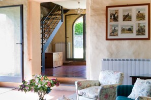 Una habitación con una escalera, un sofá, un radiador y un cuadro en la pared.