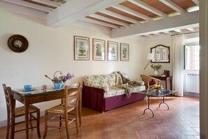 Un comedor con mesa y sillas de madera, un sofá floral y una mesa de centro de vidrio.