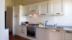 A modern kitchen with white cabinetry, a gas stove, an oven, a dishwasher, and a sink. - My Exclusive Italy - Enchanting Villa with Pool surrounded by vineyards (Rignano sull'Arno)