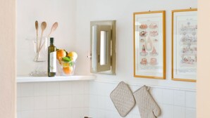 A kitchen with a white countertop, a bottle of olive oil, wooden spoons, and a framed illustration. - My Exclusive Italy - Enchanting Villa with Pool surrounded by vineyards (Rignano sull'Arno)