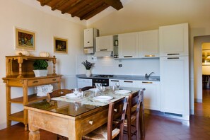 A kitchen with white cabinets, a wooden dining table set for four, and a built-in oven.