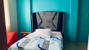 A bedroom with a bed, a nightstand, and a red chair.