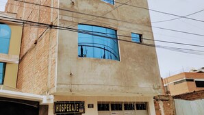Un immeuble à plusieurs étages, avec une enseigne indiquant « HOSPEDAL » au niveau du rez-de-chaussée.