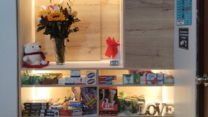 Un espace d’accueil avec une enseigne indiquant « RÉCEPTION TOSCANO SUITES » et un présentoir de boissons en bouteille.