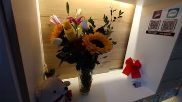 Un mostrador de recepción con un jarrón de flores, un peluche y una caja roja de regalo.
