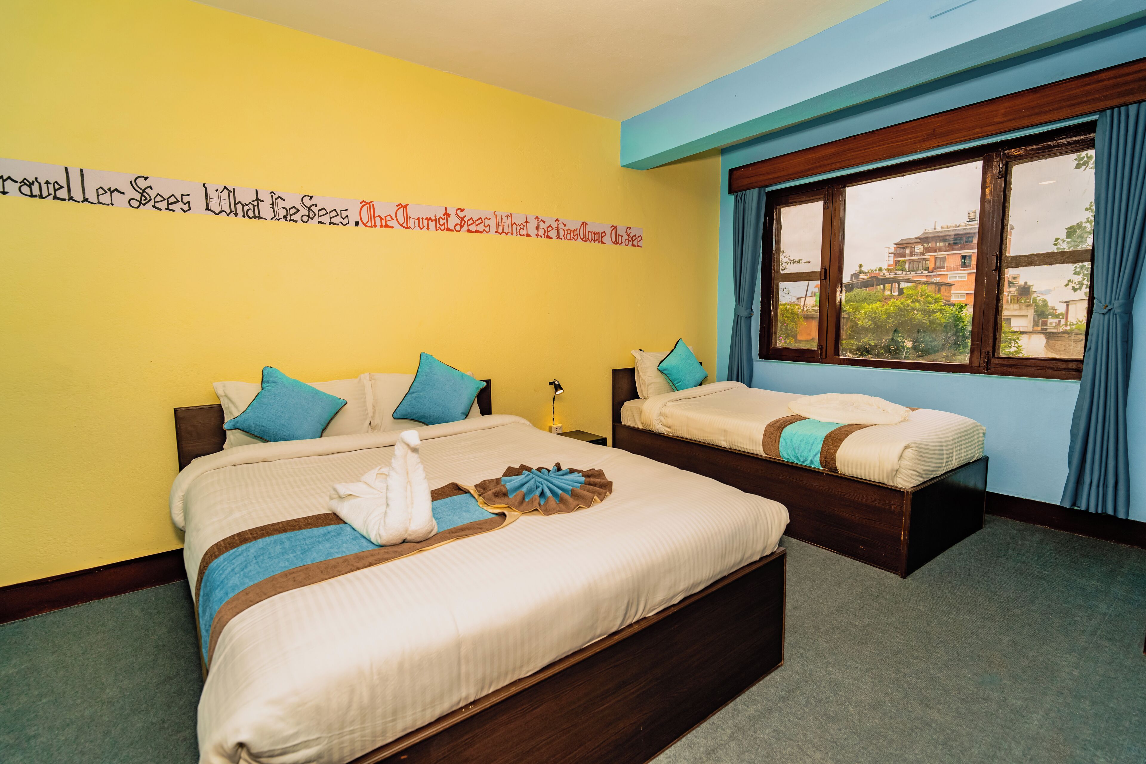 Habitación de hotel con dos camas, un ventanal grande y una frase motivacional en la pared.