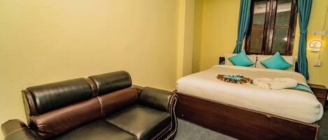 A hotel room with a bed, a sofa, and a nightstand.