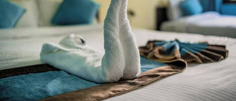 A neatly made bed with a folded towel and a brown cloth on the bed.