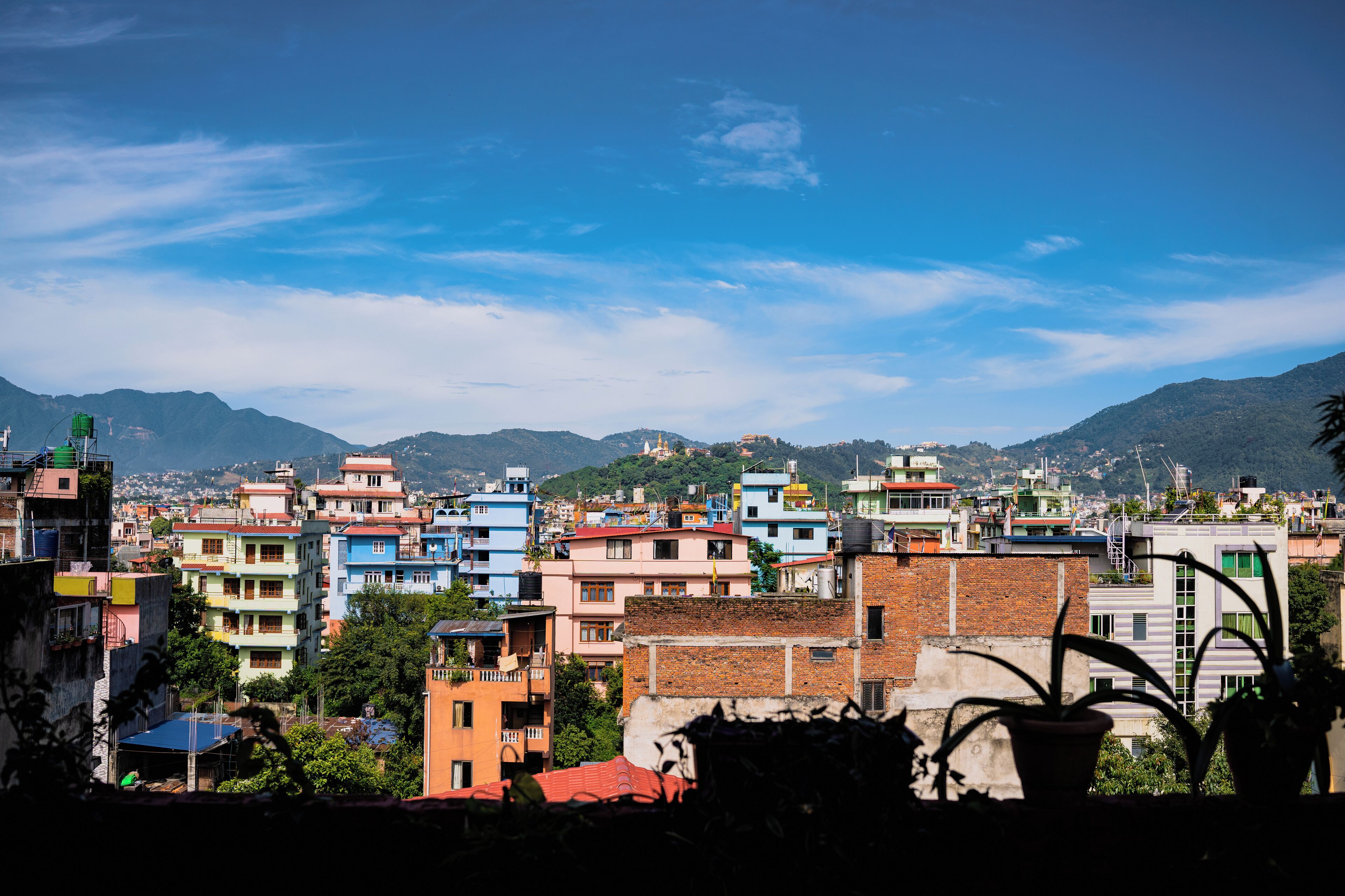 A cityscape with colorful buildings, a clear sky, and mountains in the background.