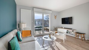 Ein modernes Wohnzimmer mit einer Couch, einem Couchtisch und einem an der Wand befestigten Fernseher.