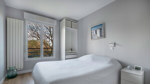 Ein Schlafzimmer mit einem Bett, einem Nachttisch, einem Fenster und einem Wandregal.