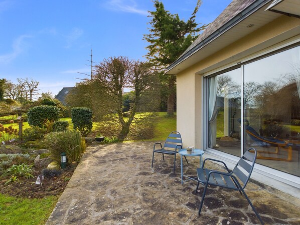 A patio with stone flooring, two metal chairs, and a table. - Spacious house, garden, ideal 6 adults & 1 child (Fouesnant)