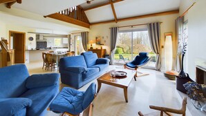 Ein geräumiges Wohnzimmer mit einem blauen Sofa, einem Holztisch und einem blauen Sessel.