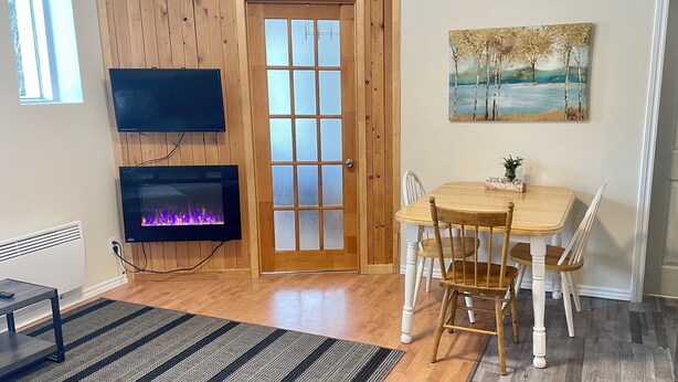 Una habitación acogedora con chimenea, una mesa de comedor con sillas y un cuadro en la pared.
