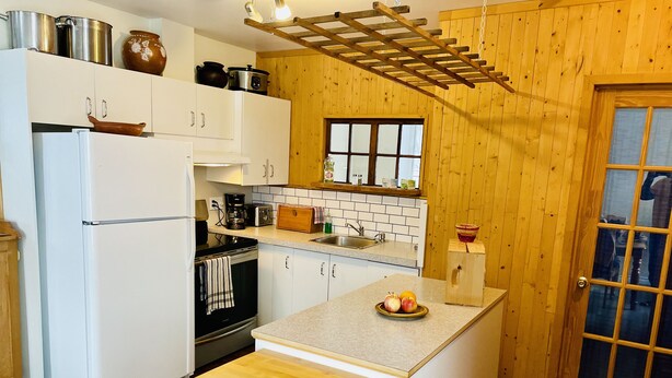 Une cuisine compacte avec des meubles blancs, un îlot central en bois et un petit évier.