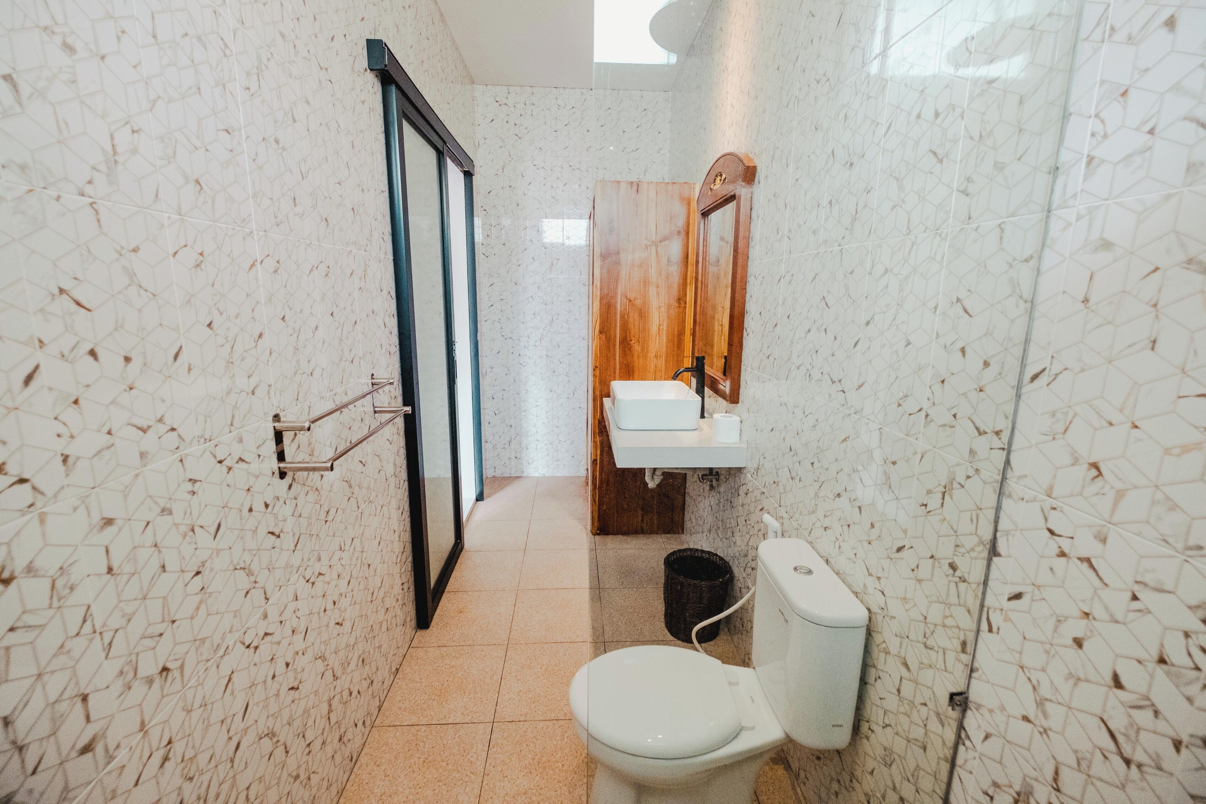 A bathroom with a white toilet, a wooden vanity, and a tiled floor.