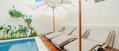 A poolside area with lounge chairs and an umbrella.