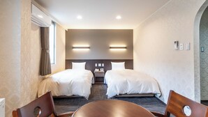 Une chambre d’hôtel avec deux lits, une table, des chaises et un bureau avec un téléphone.