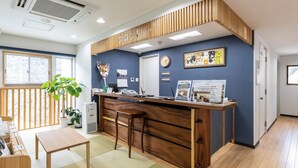Une salle d’attente avec un bureau en bois, des chaises, une plante en pot et un calendrier accroché au mur.