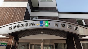 Un bâtiment moderne dont l’entrée est marquée par un panneau incurvé affichant un logo et du texte en japonais.