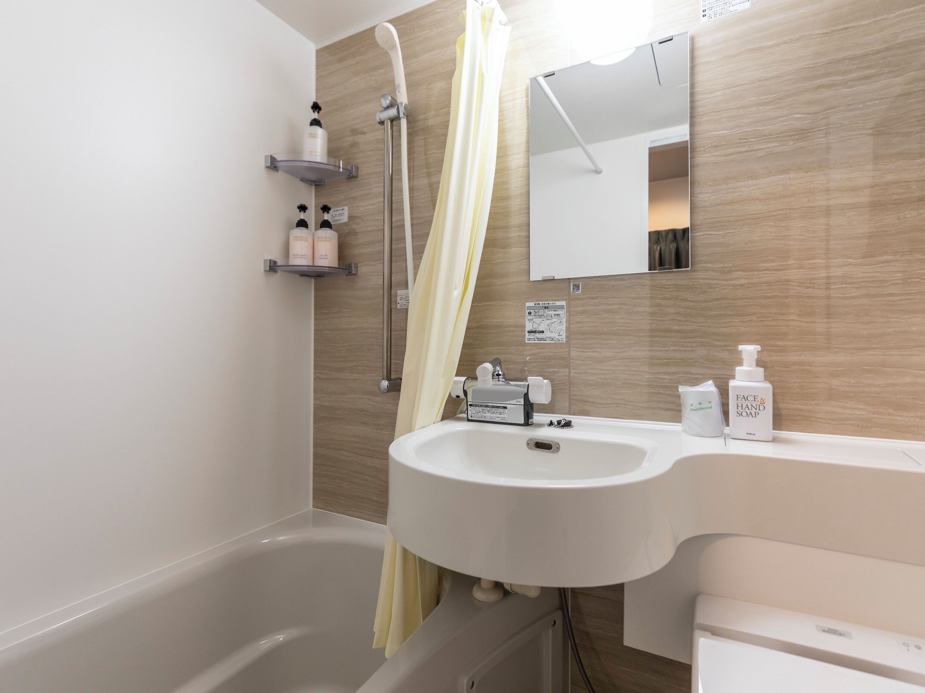 A modern bathroom with a bathtub, a sink, and a shower. There are toiletries on the sink and a showerhead above the bathtub.