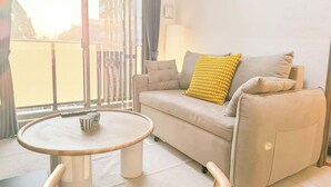 A modern living room with a sofa, a round coffee table, and a view through a large window. - Triphome Sugamo 2024 New 3 mins 2 stations 15 (Toshima City)