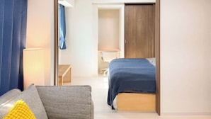 Ein modernes Hotelzimmer mit Bett, Sofa, Schreibtisch und Kleiderschrank.