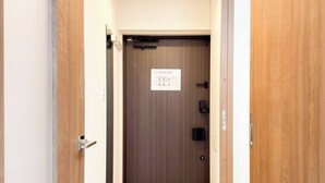 Ein schmaler Flur mit Holztüren, einem Schild an der Tür und einer Leuchte an der Decke.