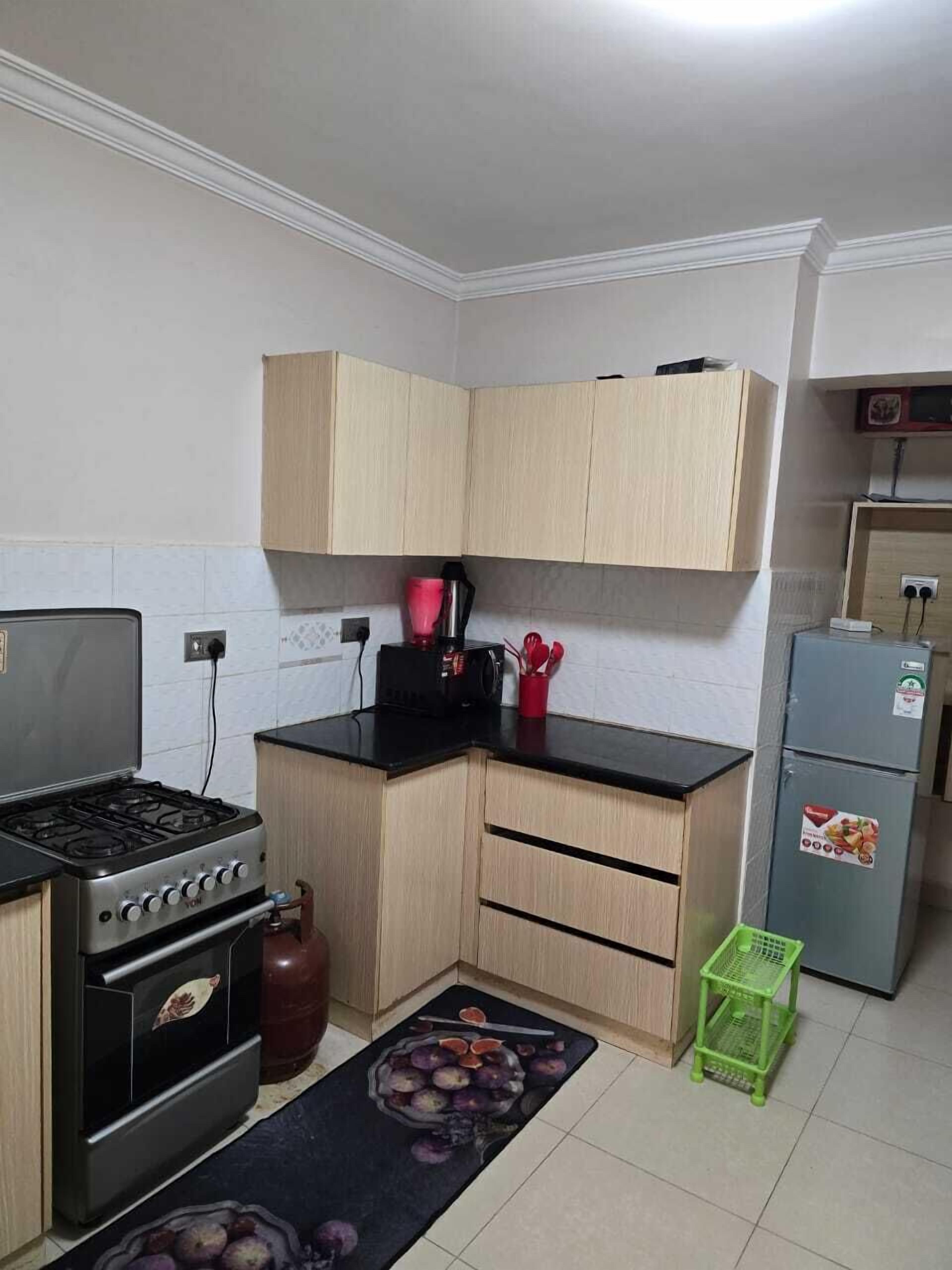 Una cocina compacta con gabinetes de madera, estufa a gas, refrigerador y una pequeña encimera.