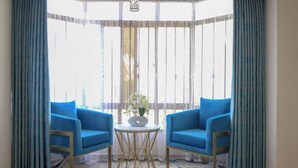A room with two blue armchairs, a small round table, and a vase with flowers. - Shawmut Suites Nakuru (Nakuru)