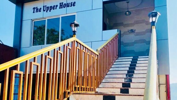 Una escalera conduce a un edificio con la señalización "The Upper House", con una barandilla amarilla y un farol en la parte superior.