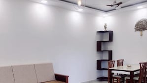 Una sala de estar moderna con sofá, mesa de comedor, sillas y ventilador de techo.