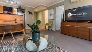Una sala de estar moderna con una mesa de centro de vidrio, un televisor y un mueble de madera.