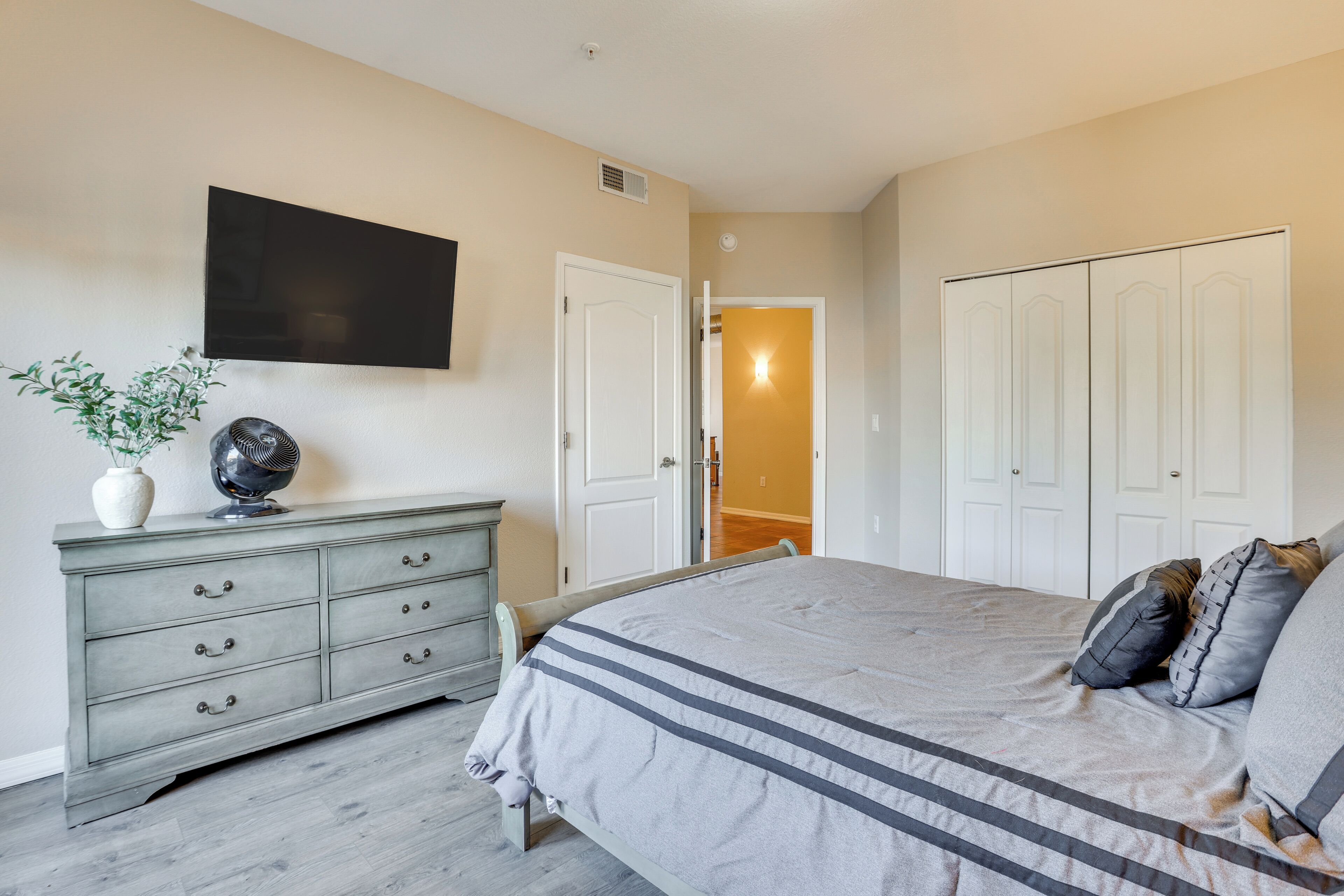 A bedroom with a bed, dresser, and a TV mounted on the wall.