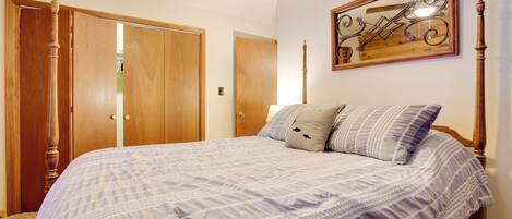 A bedroom with a large bed, wooden wardrobe, and a ceiling fan.