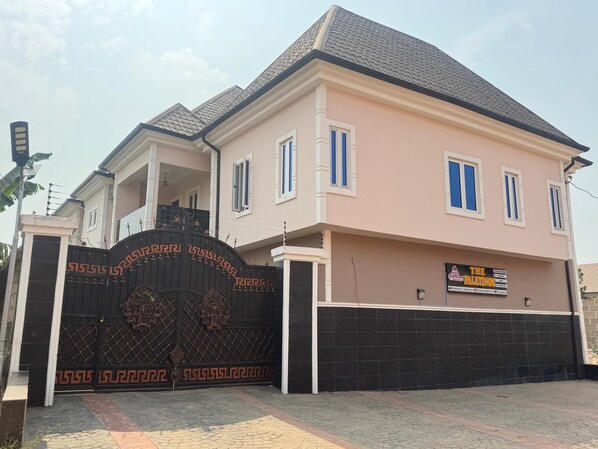 A two-story house with a black gate, a balcony, and a sign for 'The Paletinos' restaurant.