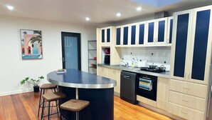 A modern kitchen with a central island, bar stools, and a dining area. - Lipscombe Mt Wellington view luxury house (HOBART)