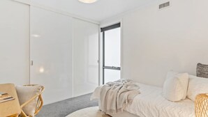 A modern bedroom with a bed, a chair, a window, and a wardrobe. - Lipscombe Mt Wellington view luxury house (HOBART)